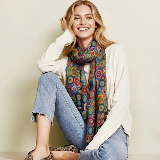 Woman wearing a colorful scarf and sitting on a couch with a neutral background